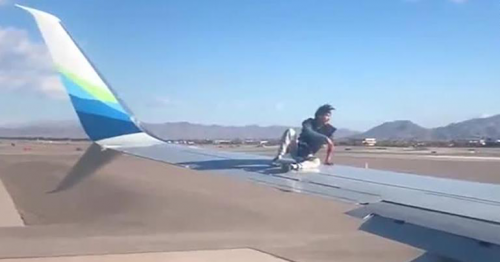 Man was taken into custody after he climbed onto the wing of an airplane preparing to takeoff